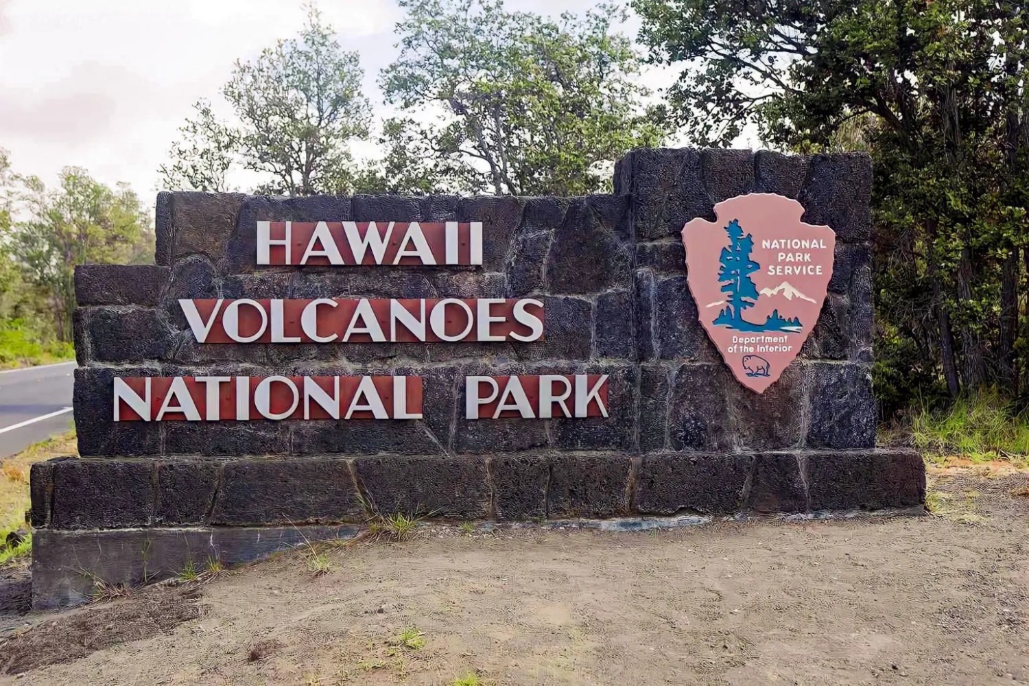 Sign for Hawaii Volcanoes National Park with trees in the background.