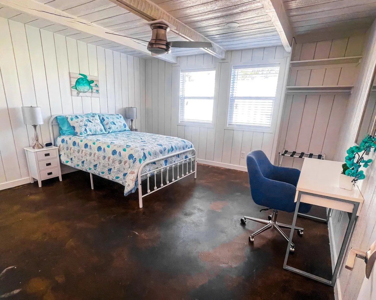 Bedroom with bed, nightstand, desk, chair, and ceiling fan, decorated in blue and white theme.